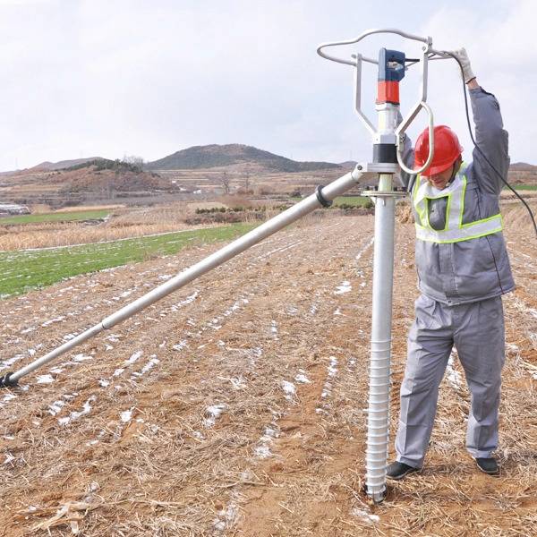 A worker is installing ground screw with 14000 W 120 V electric ground screw driver.