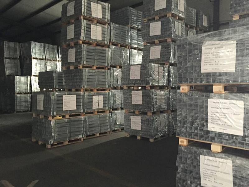 Several pallets of post spikes are placed in the warehouse tidily.